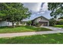 Beautifully landscaped front yard with lush green grass, a mature tree, and an attached two-car garage at 3115 Westridge Dr, Holiday, FL 34691