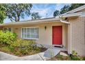 Close-up of the home's entrance with red door, neat landscaping, and house number at 321 Belle View Ave, Temple Terrace, FL 33617