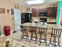Open kitchen featuring a spacious island with barstool seating, stainless steel appliances, and dark wood cabinetry at 3313 San Moise Pl, Plant City, FL 33567
