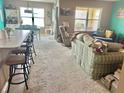 Bright and airy living room featuring large windows and neutral carpeting with a cozy sofa and recliner at 3313 San Moise Pl, Plant City, FL 33567