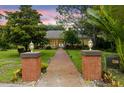 Inviting home entrance with brick pillars and a well-manicured lawn at 3402 Melissa Country Way, Lutz, FL 33559