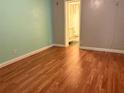Bedroom with wood-look floors, neutral walls, and view into an ensuite bathroom at 4020 55Th N St # 1106, Kenneth City, FL 33709