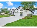 Side view of a charming home with a three-car garage, landscaped lawn, and blooming crape myrtle tree at 679 Challice Dr, Spring Hill, FL 34609