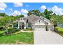 Charming single-story home with a manicured lawn, flowering shrubs, and a three car garage at 679 Challice Dr, Spring Hill, FL 34609