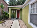 Charming front porch with red door, decorative wreath, and unique round window at 8313 Arabian Dunes Pl, Riverview, FL 33578