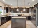 Traditional kitchen with dark cabinets, stainless steel appliances, granite countertops, and a kitchen island at 12316 Streambed Dr, Riverview, FL 33579