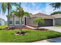 Beautiful home featuring a lush green lawn, mature palm trees, and a two-car garage at 13910 Chalk Hill Pl, Riverview, FL 33579