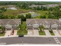 An aerial view shows the community townhomes in a landscaped neighborhood with a water feature at 1395 White Fox Run, Lutz, FL 33549