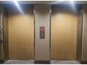 Image of a pair of elevators with wood paneled doors and illuminated floor indicators at 2333 Feather Sound Dr # A401, Clearwater, FL 33762