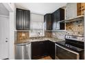 Updated kitchen with black cabinetry, granite countertops, stainless steel appliances and tile backsplash at 2834 Somerset Park Dr, Tampa, FL 33613