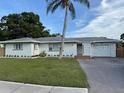 Charming single-story home with a well-maintained lawn, a palm tree and a driveway at 3118 Adrian Ave, Largo, FL 33774