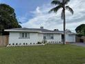 Charming single-story home with a well-maintained lawn, a palm tree and a driveway at 3118 Adrian Ave, Largo, FL 33774