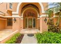 Elegant front entrance with arched doorway, modern lighting, and lush landscaping at 3308 Landing Pl, Palm Harbor, FL 34684