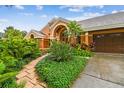 Inviting home showcasing a brick path, mature landscaping, and an attached garage at 3308 Landing Pl, Palm Harbor, FL 34684