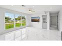 Spacious living room with sleek marble floors, large windows, and a modern ceiling fan at 7930 Jeffery Ave, North Port, FL 34287