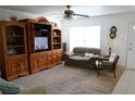Comfortable living room featuring a neutral sofa, entertainment center, and natural light filtering through a window at 101 Cambridge Trl # 205, Sun City Center, FL 33573
