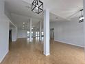 Bright, open-concept living space with wood-look tile flooring and modern light fixtures at 13551 Banner Rd, Spring Hill, FL 34609