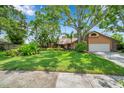 Beautiful home surrounded by lush landscaping on a manicured lawn with blue skies in the background at 1695 Cinnamon Ln, Dunedin, FL 34698