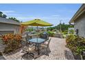 Brick patio with dining table, umbrella, and green shrubbery at 184 Hunter Ct, Palm Harbor, FL 34684