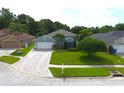 Beautiful single-story home showcasing a paver driveway, lush lawn, and mature trees at 1842 Ridgelake Ct, Wesley Chapel, FL 33543