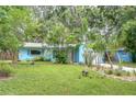 Inviting blue home with tropical landscaping and vibrant greenery, providing a serene and picturesque curb appeal at 2051 Indigo Dr, Clearwater, FL 33763