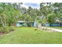 Landscaped front yard with a charming blue house, surrounded by lush trees and well-maintained greenery at 2051 Indigo Dr, Clearwater, FL 33763