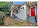 Side and rear view of a home with stucco exterior, red doors, and wrought iron railings at 2808 N Highland Ave, Tampa, FL 33602