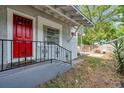 Side entrance with a bright red door, iron railings, and an adjacent yard space at 2808 N Highland Ave, Tampa, FL 33602