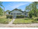 Quaint bungalow with a screened front porch and a green, fenced front lawn at 3008 E Wilder Ave, Tampa, FL 33610