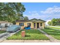 Charming bungalow with a well-maintained lawn and covered car during the day at 3201 E Mcberry St, Tampa, FL 33610