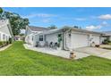 Inviting home exterior featuring a cozy patio area, lush green lawn, and attached garage with awning at 3271 Mcmath Dr, Palm Harbor, FL 34684