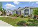 Well-maintained single-Gathering home, boasting colorful landscaping, and a freshly-cut lawn on a sunny day at 3457 Foxhall Dr, Holiday, FL 34691