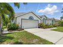 Angle view of the home featuring an attached two-car garage with lush landscaping bordering the driveway at 3457 Foxhall Dr, Holiday, FL 34691