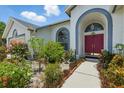 Close up of the front entrance features a vibrant red double door and lush landscaping at 3457 Foxhall Dr, Holiday, FL 34691
