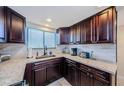 Well-lit kitchen featuring dark wood cabinets, granite countertops, and tile backsplash at 6009 Sea Ranch Dr # 306, Hudson, FL 34667