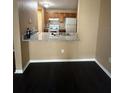 View of the kitchenette from living room with dark wood floors, granite countertop, and oak cabinets at 8517 Island Breeze Ln # 207, Temple Terrace, FL 33637