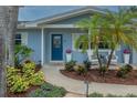 Inviting entryway with a blue front door, lush landscaping, and cozy seating area at 111 Carlyle Dr, Palm Harbor, FL 34683