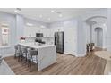 Modern kitchen features white cabinets, stainless steel appliances, a large island with seating, and wood-look floors at 14521 Mirasol Manor Ct, Tampa, FL 33626