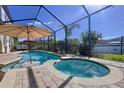 Inviting screened-in pool and spa with a surrounding brick patio and lush landscaping at 1947 Marshberry Ct, Trinity, FL 34655