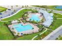 Aerial view of the community pool featuring two pools, ample seating and manicured landscaping at 2898 Living Coral Dr, Odessa, FL 33556