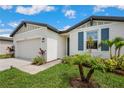 Close up exterior view of the home showcasing blue shutters, a two car garage and lush landscaping at 3082 Forrest Plum Ct, Zephyrhills, FL 33540