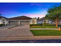 Charming single-story home with a well-manicured lawn and a two-car garage, under a beautiful twilight sky at 31814 Larkenheath Dr, Wesley Chapel, FL 33543