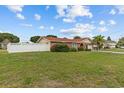 Picture of the house's facade showcasing the lawn, fence, and driveway, under a sky filled with fluffy clouds at 326 Circle Dr, Palm Harbor, FL 34683