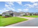 Street view of a well-maintained single-story house with a grey exterior and manicured landscaping at 6226 165Th E Dr, Parrish, FL 34219