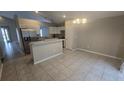 Well-lit kitchen featuring tile flooring, stainless steel refrigerator, modern white cabinets, and breakfast bar at 6517 Summer Cove Dr, Riverview, FL 33578