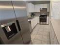 Close-up of a modern kitchen with stainless steel appliances, white cabinets, and tile flooring at 6517 Summer Cove Dr, Riverview, FL 33578