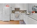 Well-lit kitchen featuring white cabinets, stainless steel appliances, and stylish backsplash at 1044 Kennewick Ct, Wesley Chapel, FL 33543