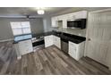 Modern kitchen featuring stainless steel appliances, sleek black countertops, and stylish wood-look flooring at 1215 Windsor Cir, Brandon, FL 33510
