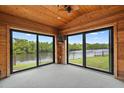 Bright sunroom with wood-paneled walls, carpet floors and large glass doors with a scenic view of the water at 1721 Allens Creek Dr, Clearwater, FL 33764