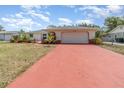 Beautiful single-story home with a spacious driveway and a well-manicured lawn under a partly cloudy sky at 1839 Neptune Dr, Englewood, FL 34223